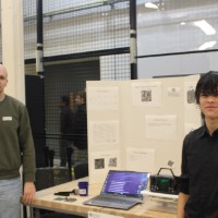Two students standing next to a karaoke project.